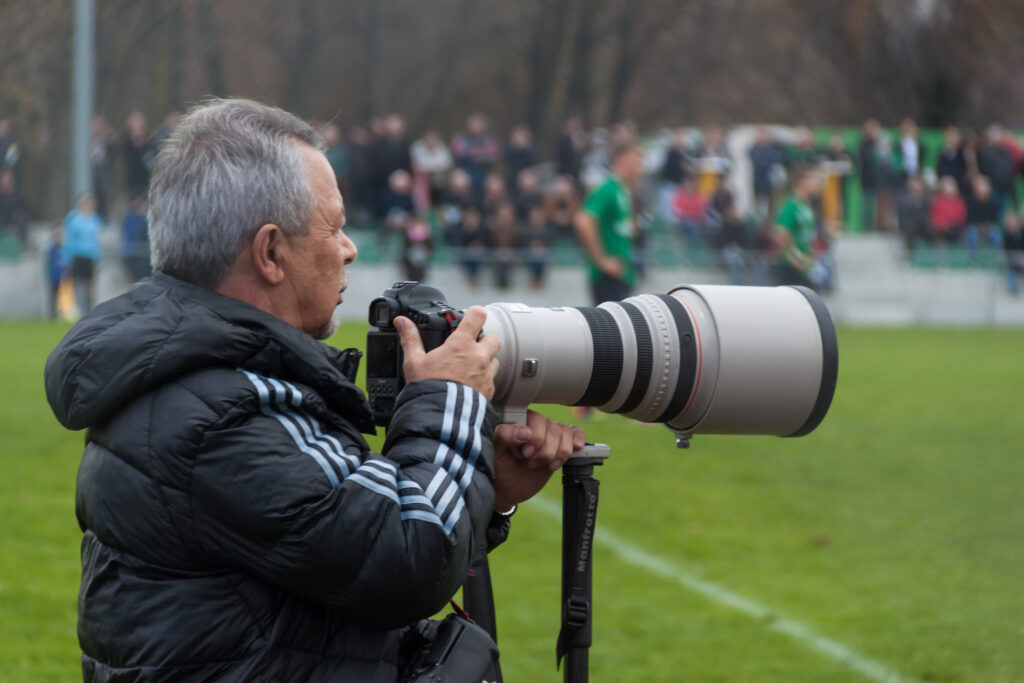Fotógrafo deportivo con teleobjetivo junto a un campo de fútbol en Suiza en 2012